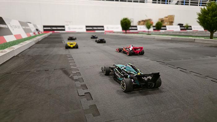 Immersive F1 environment — turf, scale trees, and branded barriers